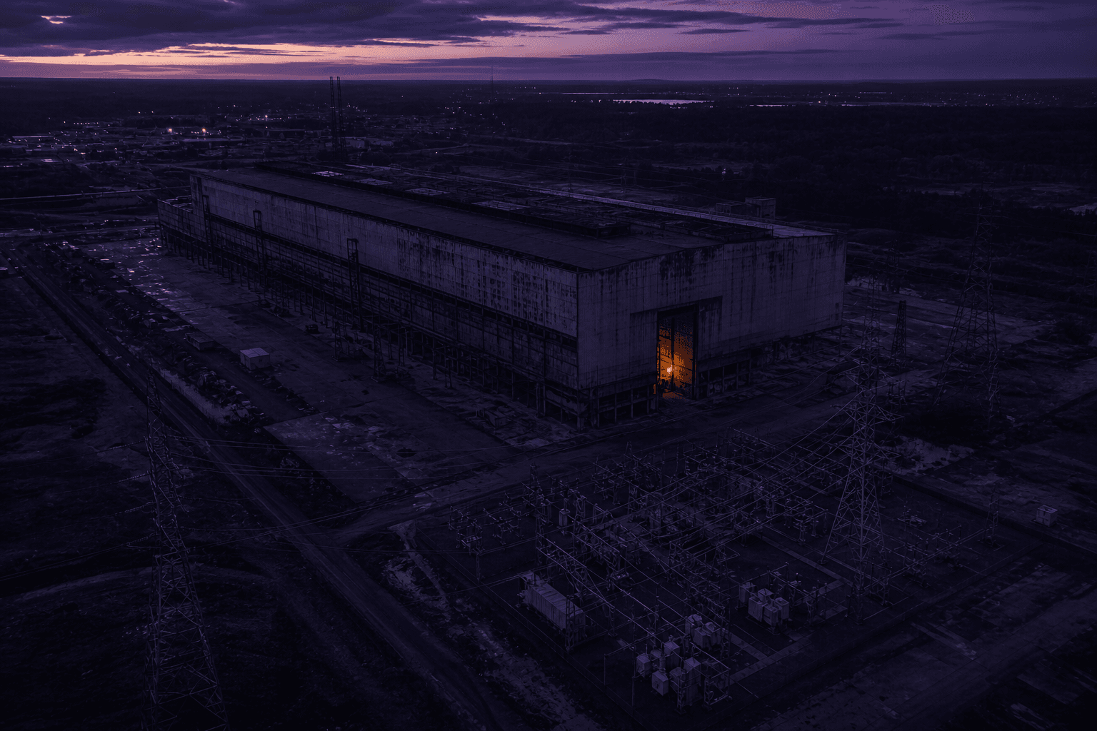 Aerial dusk view of a retired industrial site with live substation and high-voltage lines